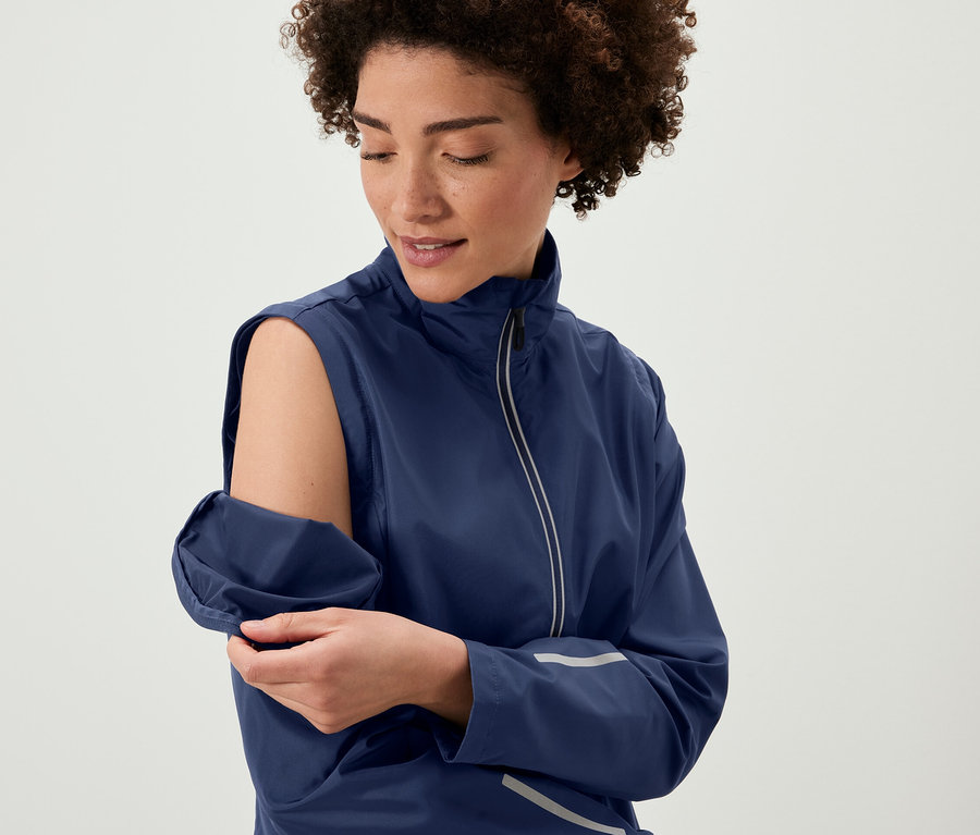 Kobieta odczepia rękawy od kurtki rowerowej 2 w 1.