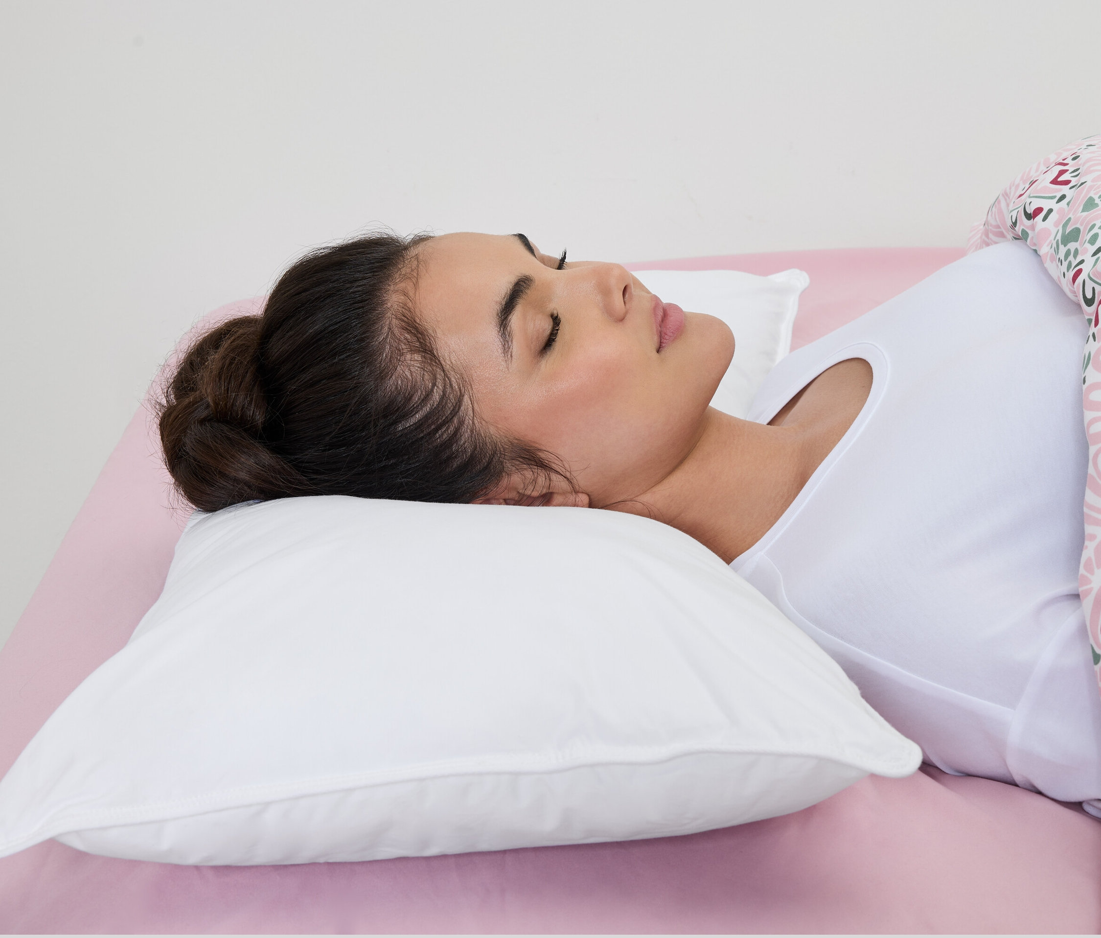 Kobieta śpi na białej poduszce wodnej irisette® na różowym prześcieradle.