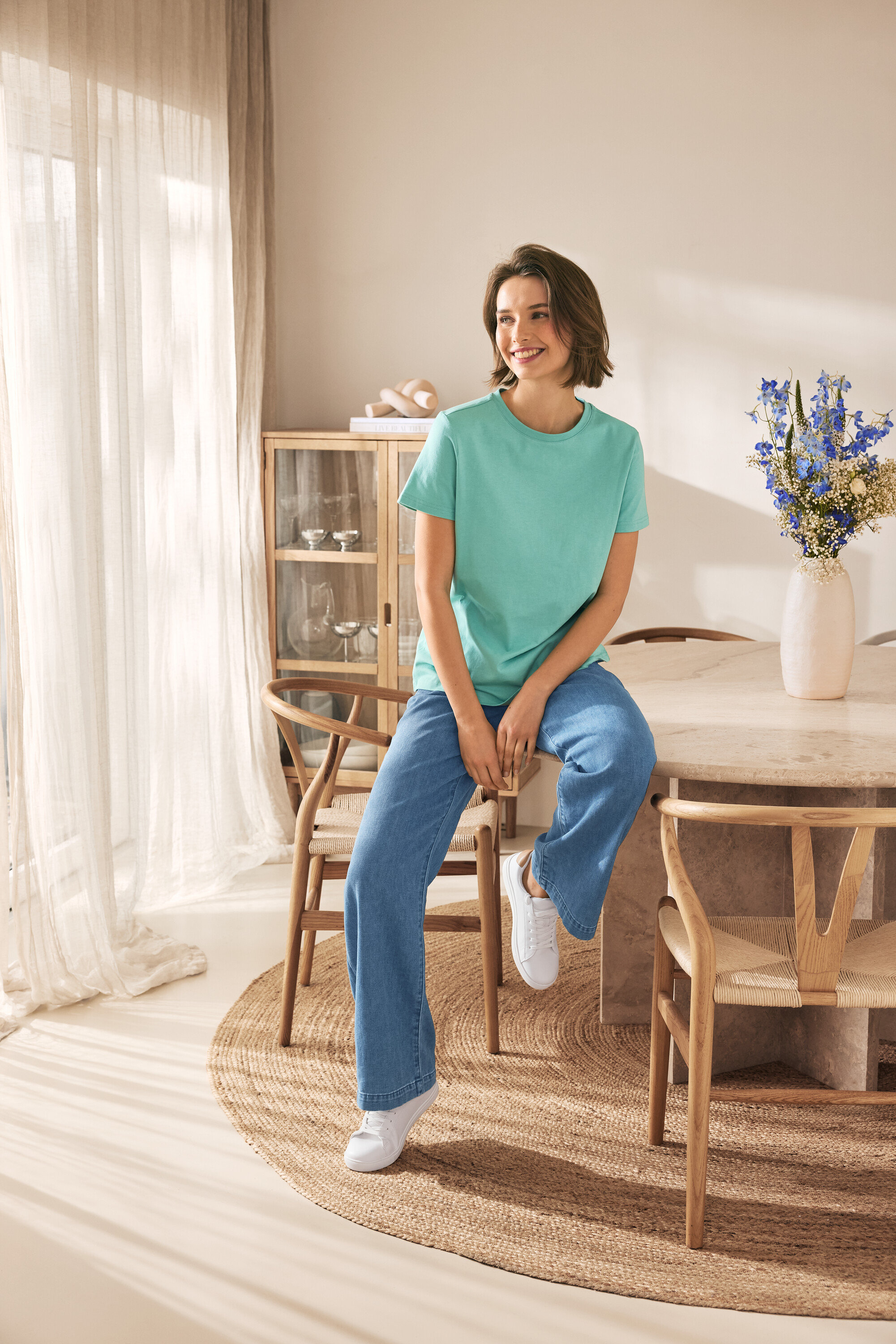 Kobieta siedzi na krześle i ma na sobie skórzane sneakersy.