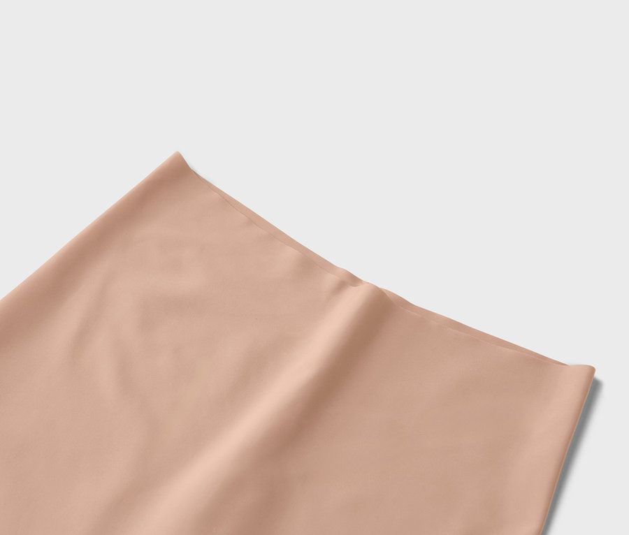 Zbliżenie jednolitej tkaniny w kolorze brzoskwiniowym.