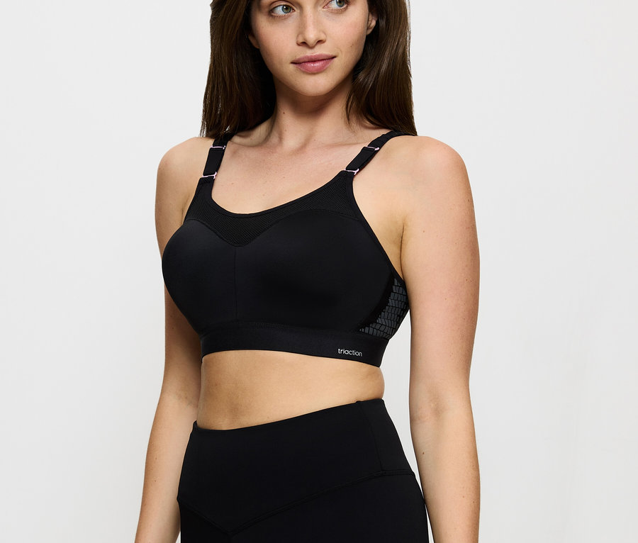 Kobieta ma na sobie czarny biustonosz sportowy Triaction i legginsy.
