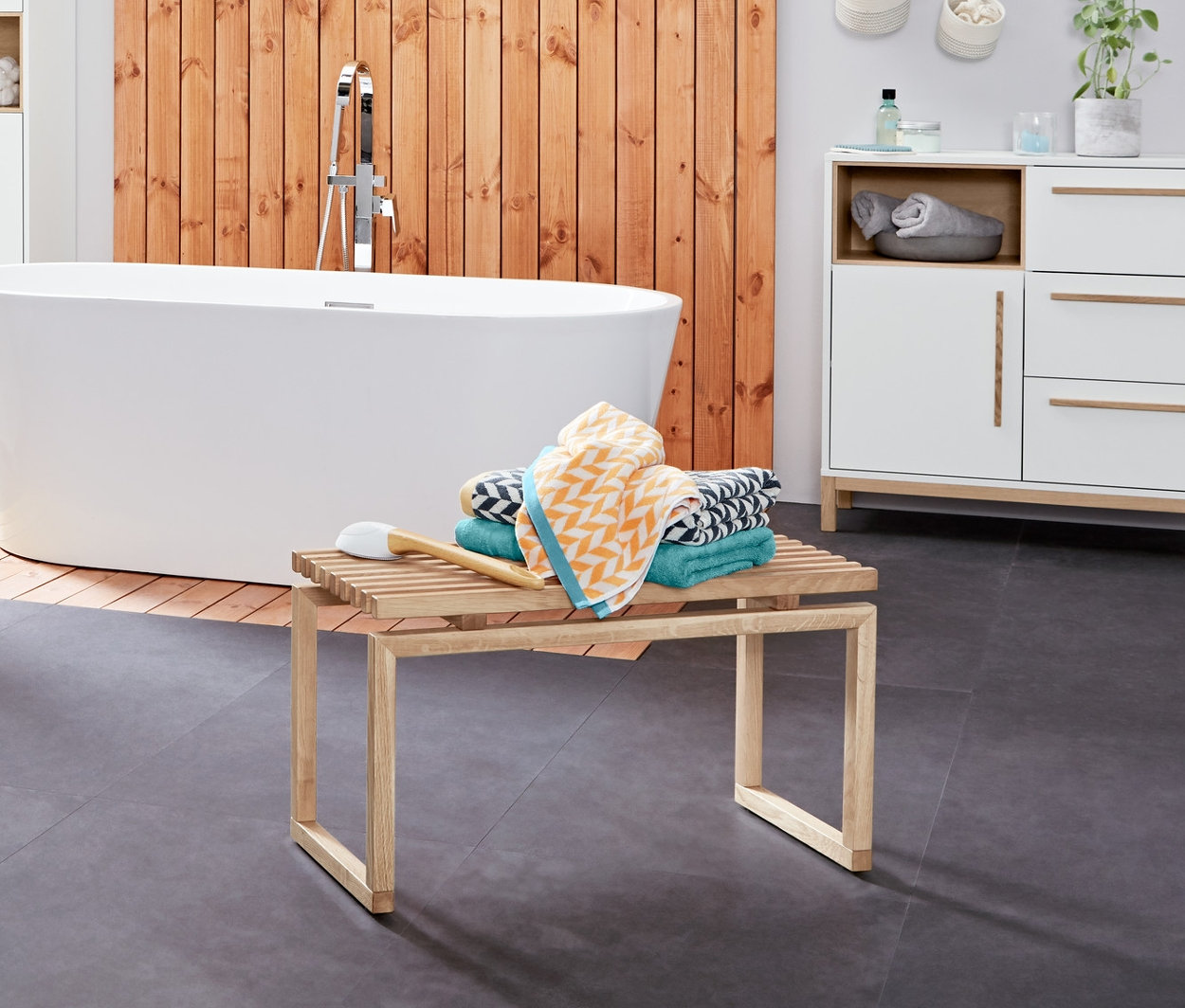 Wnętrze łazienki z szafką pod umywalkę »Eklund« z dwiema szufladami, drabinką na tekstylia i żakardowymi ręcznikami kąpielowymi.