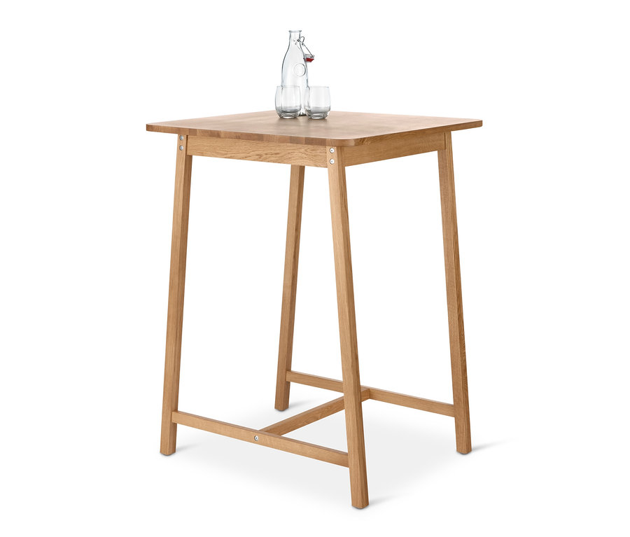 Na drewnianym stoliku barowym stoi butelka wody i dwie szklanki.