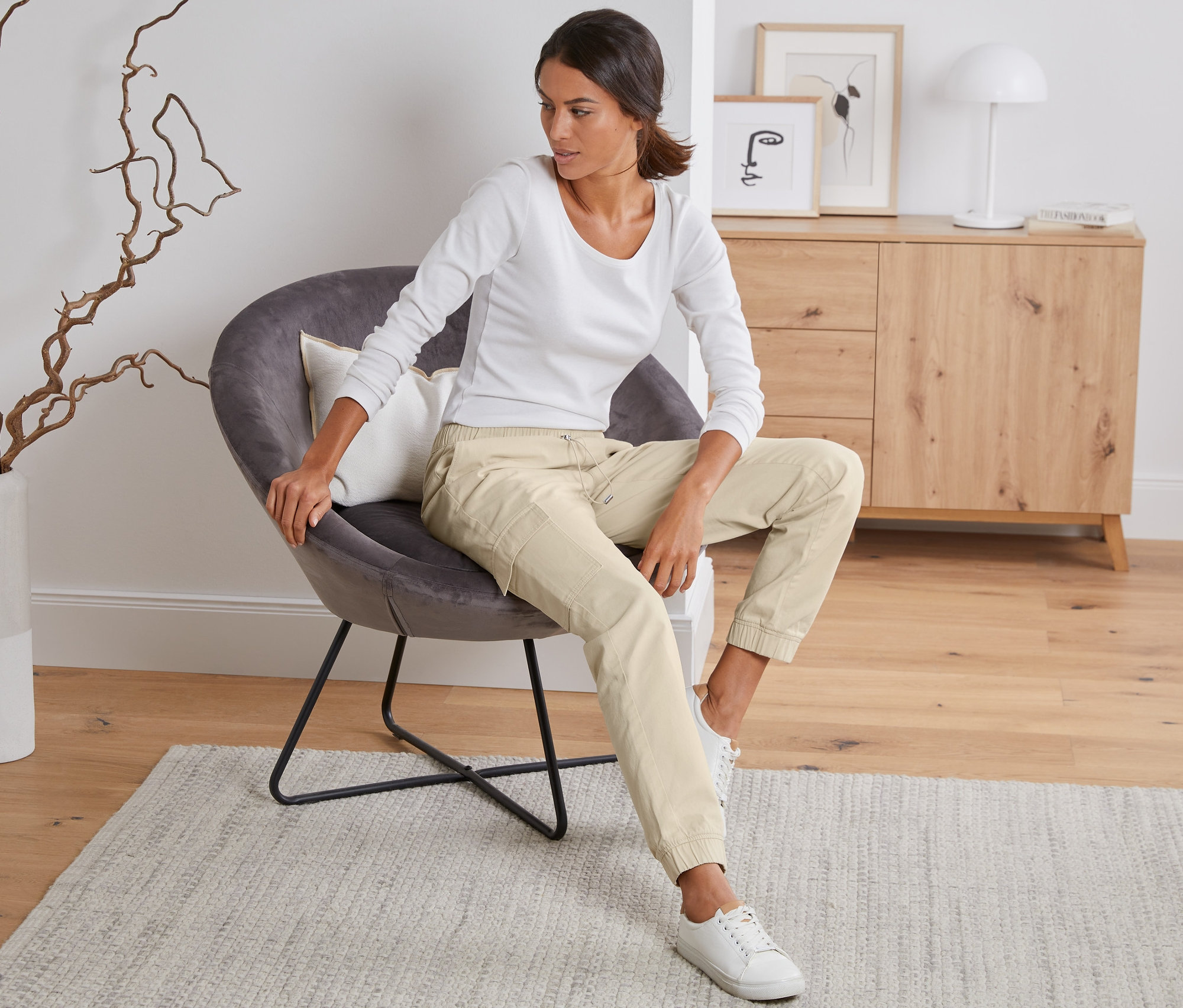 Kobieta siedzi w fotelu i ma na sobie spodnie bojówki.