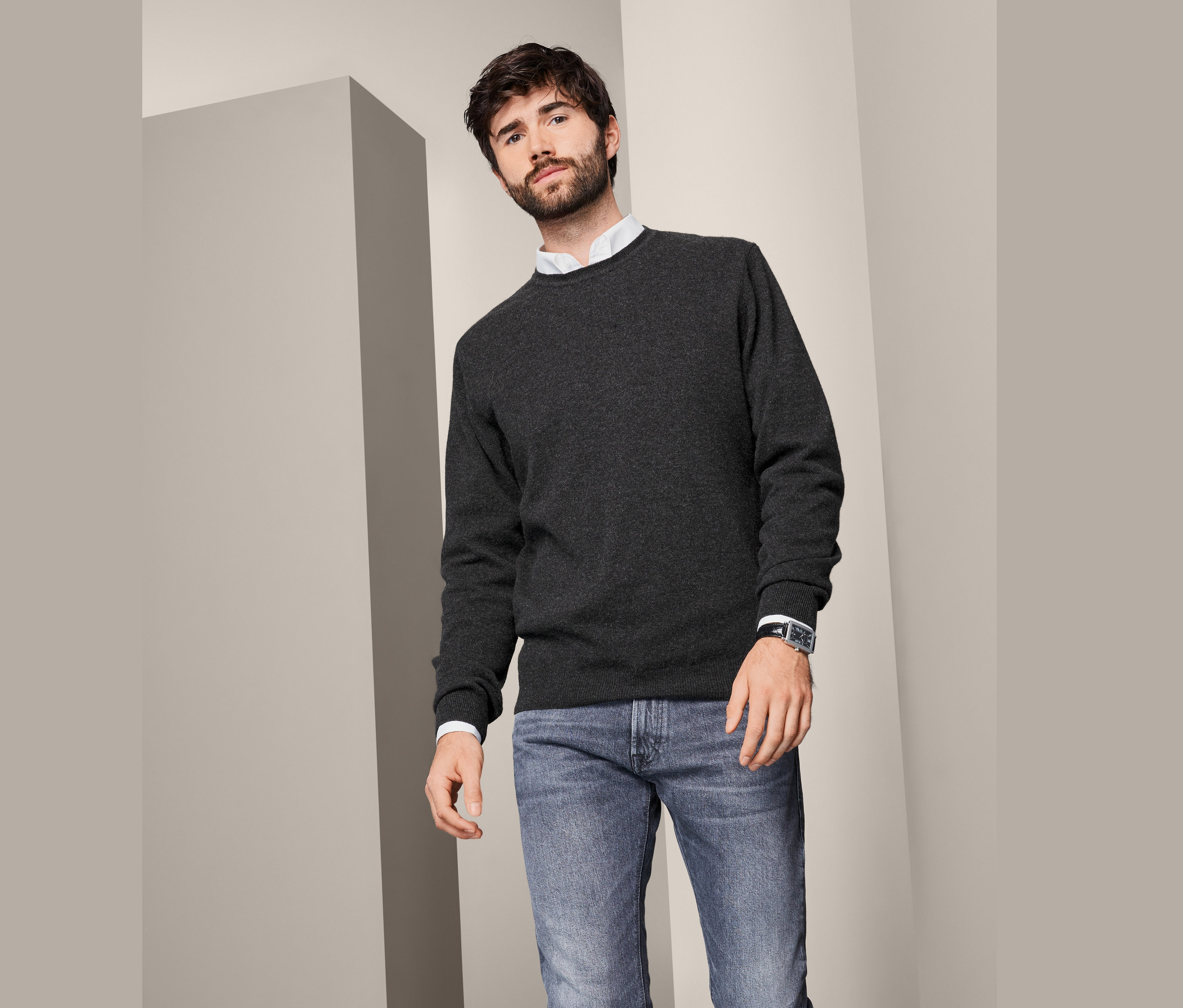 Mężczyzna ma na sobie męski sweter z kaszmiru z okrągłym wycięciem pod szyją, dżinsy i zegarek.