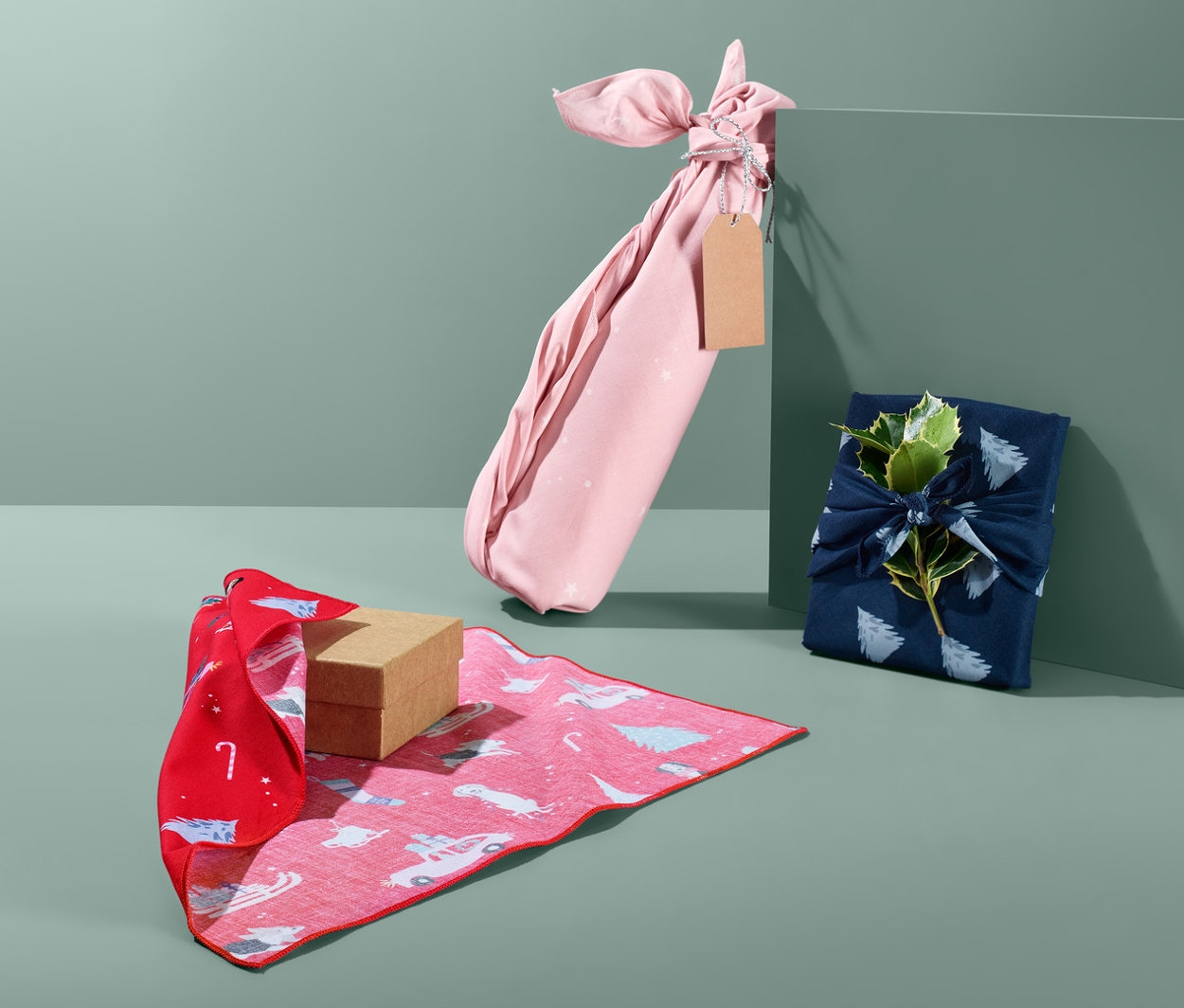 Trzy prezenty zapakowane w papier świąteczny z tkaniny w różnych kolorach.