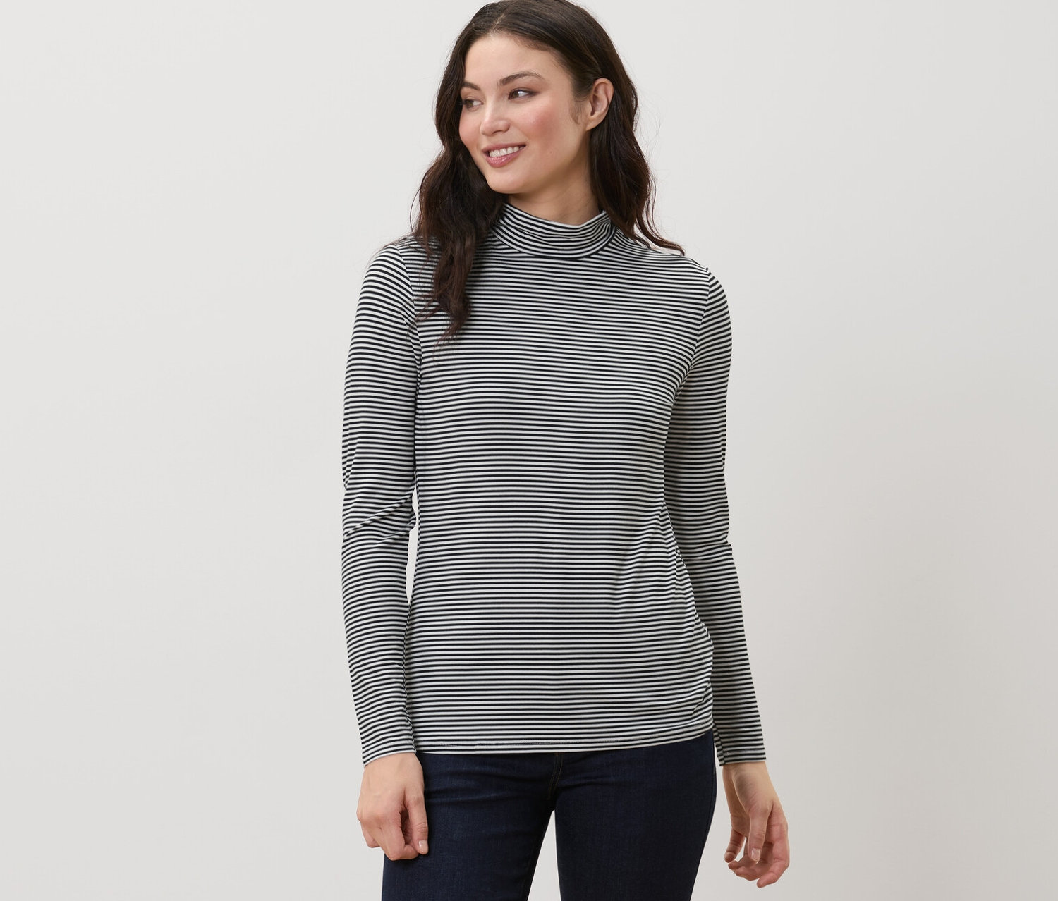 Kobieta ma na sobie bluzkę w paski ze stójką i granatowe spodnie.