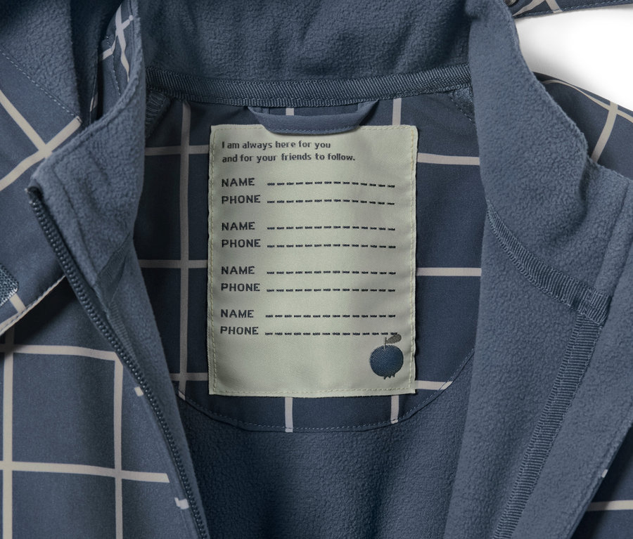 Zbliżenie na dziecięcy kombinezon softshell w kratkę z metką na imię i numer telefonu.