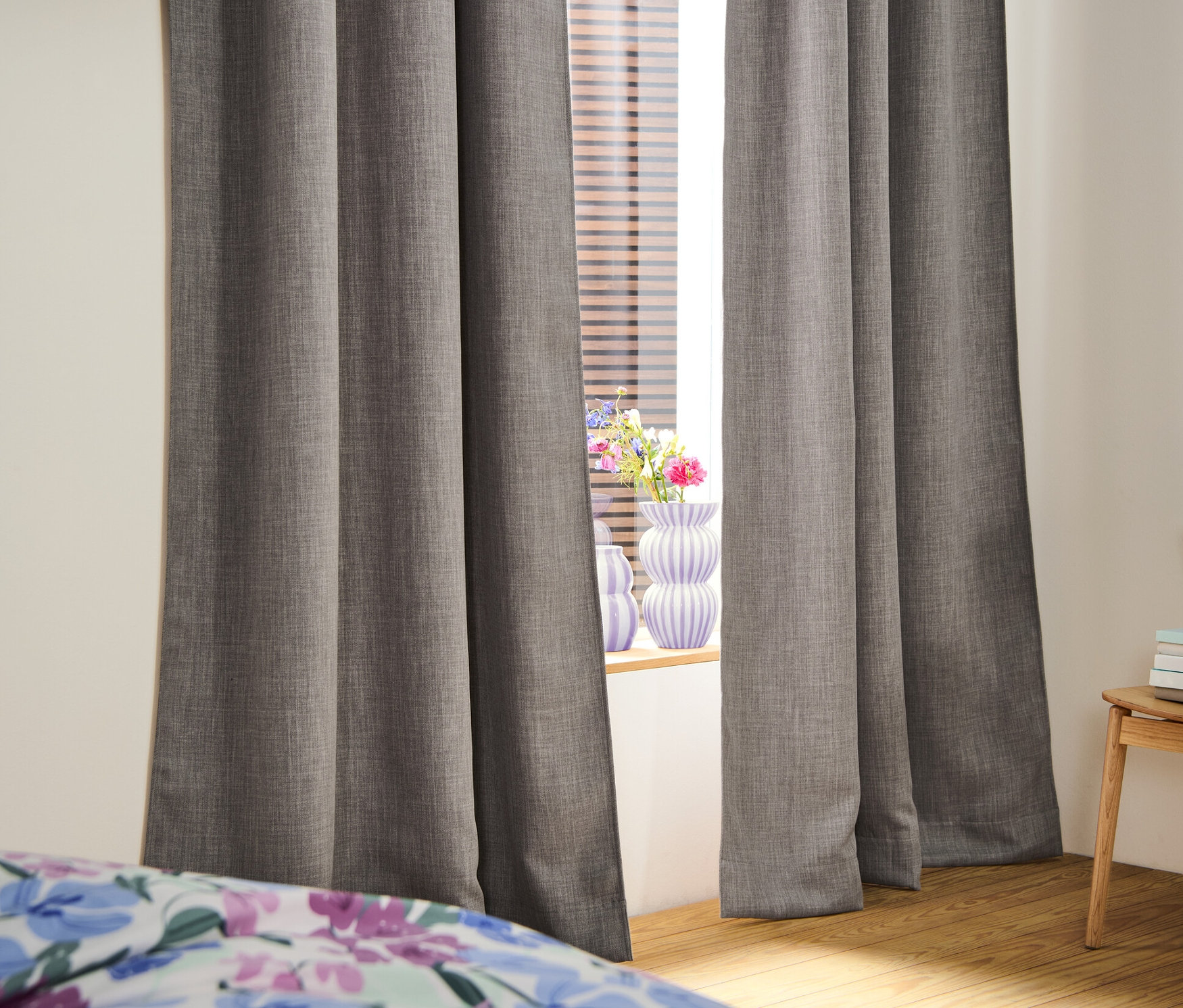 Dwie zasłony zaciemniające przy oknie. W oknach są żaluzje.