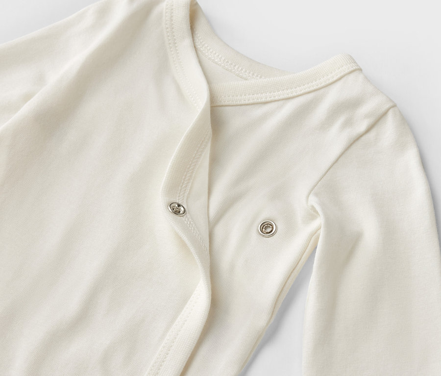 Zbliżenie na białe body niemowlęce z długim rękawem z 5-częściowego zestawu rosnącego z dzieckiem.