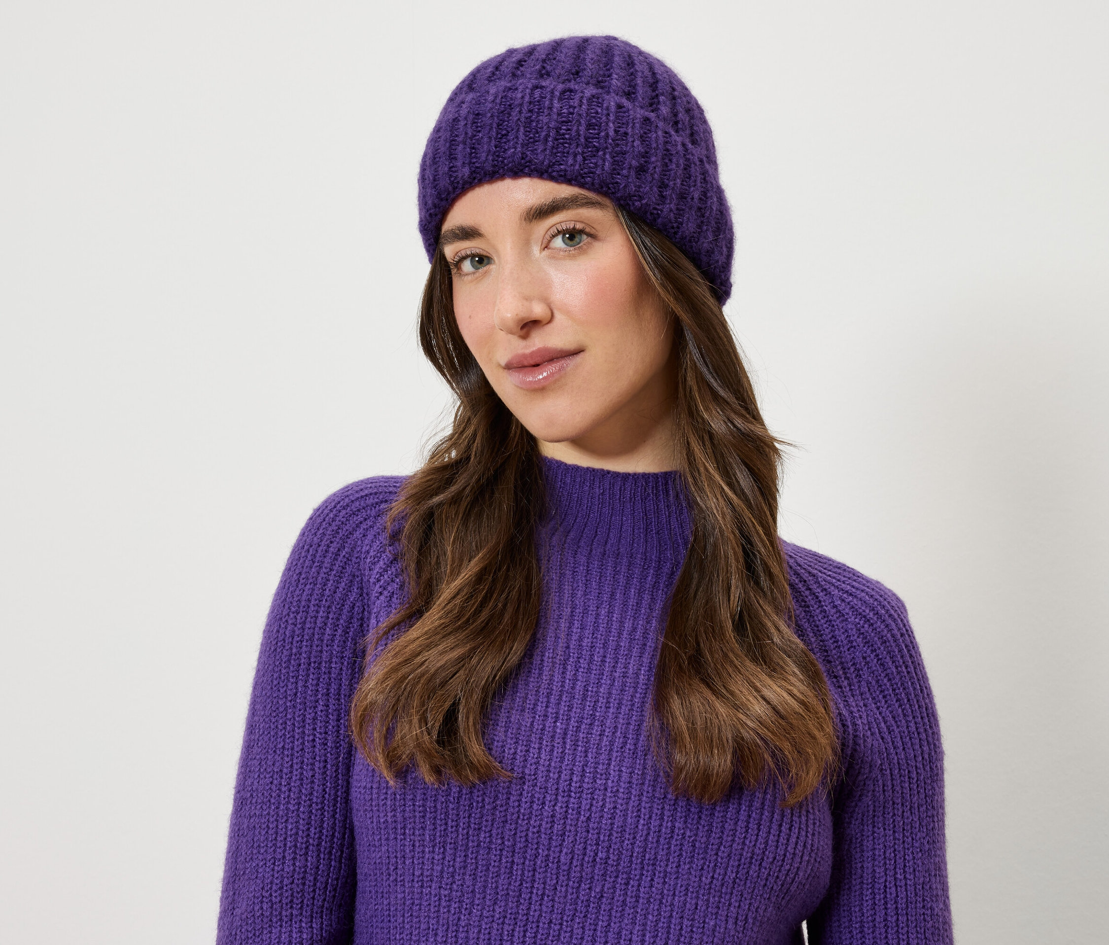Kobieta ma na sobie fioletową czapkę i sweter.