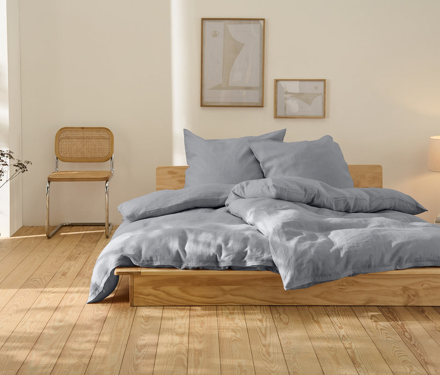 Szara lniana pościel w dużym rozmiarze na drewnianym łóżku.