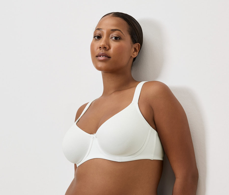 Portret kobiety o brązowej karnacji w białym biustonoszu.