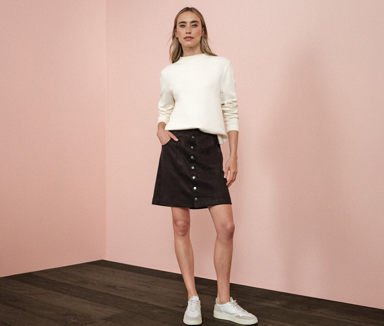 Kobieta stoi z ręką w kieszeni brązowej spódnicy welurowej od Street One.