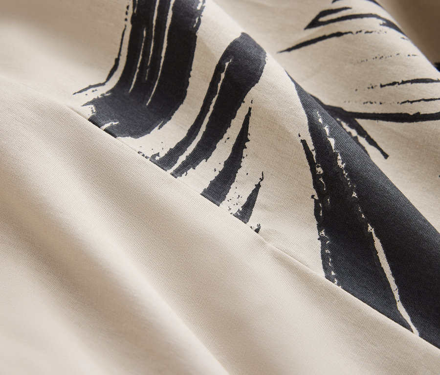 Szczegół kremowej tkaniny z granatowym, abstrakcyjnym wzorem.