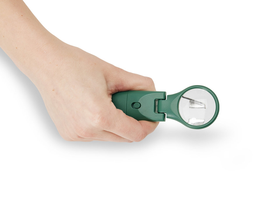 Ręka trzyma zielony przyrząd do usuwania kleszczy u zwierząt z diodą LED.