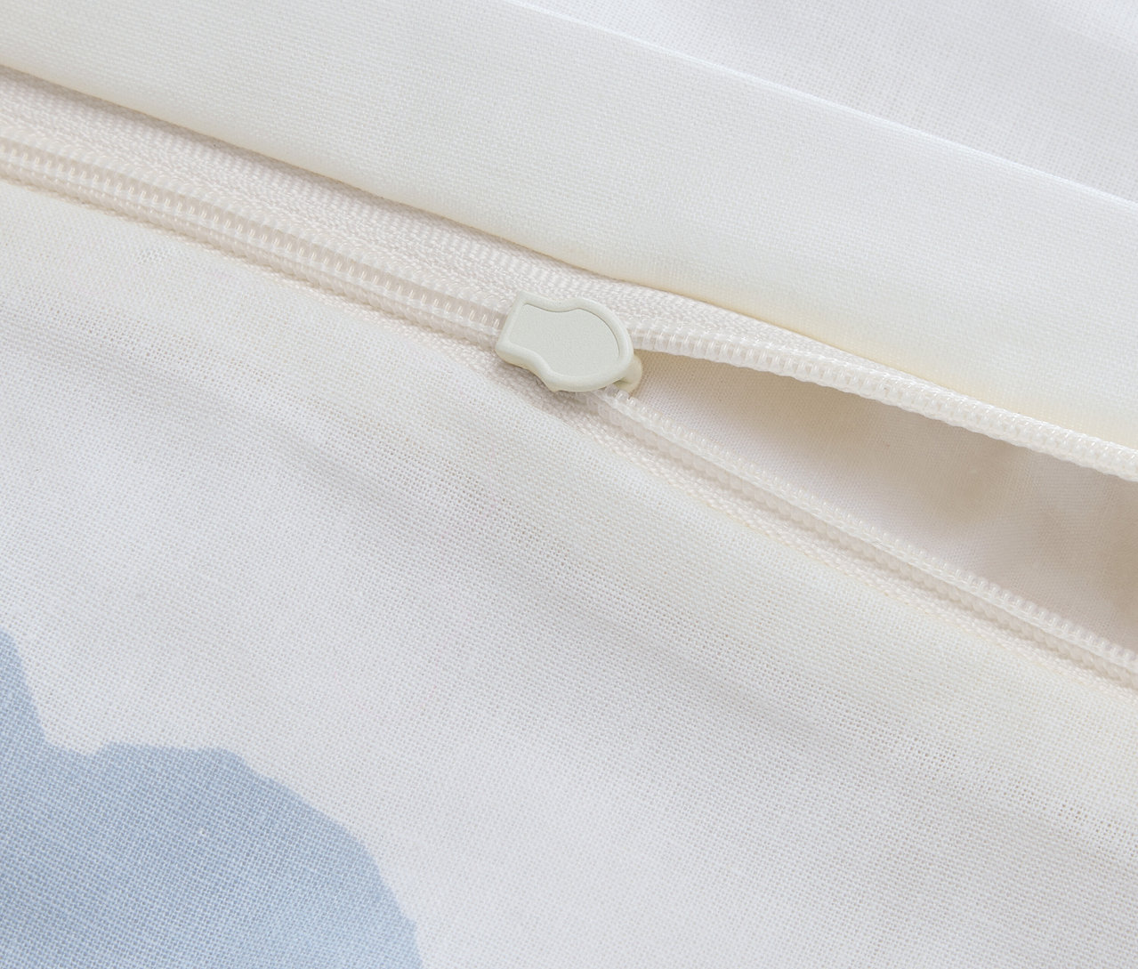 Zbliżenie na częściowo otwarty zamek błyskawiczny na białym pokrowcu z tkaniny.