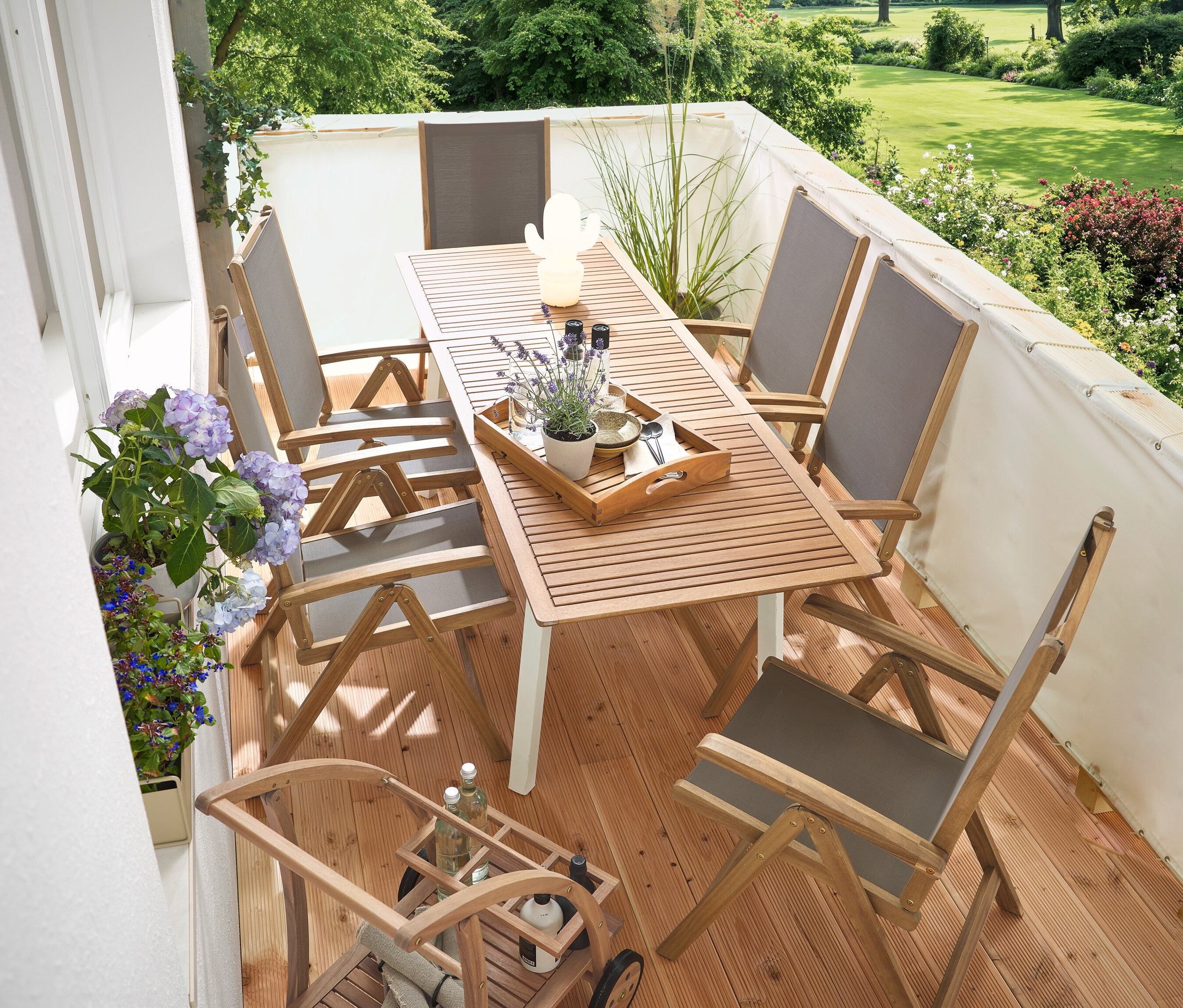 Na balkonie znajduje się wąski, rozkładany stół ogrodowy »Liska«, kremowy parawan balkonowy, barwagen z odłączaną tacą i zewnętrzna lampa stołowa LED na akumulator w kształcie kaktusa.