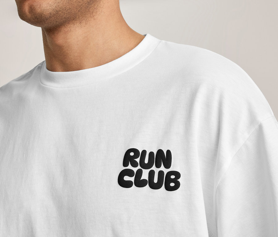 Osoba w białej koszulce sportowej z napisem „RUN CLUB” na piersi.