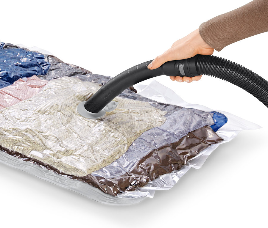 Ręka trzyma wąż odkurzacza nad próżniowym workiem do przechowywania.