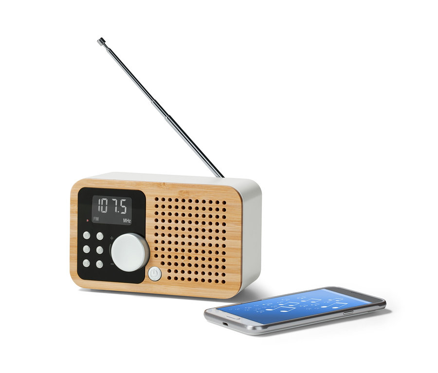 Kompaktowe radio FM »Bambus« z wysuniętą anteną stoi obok smartfona.