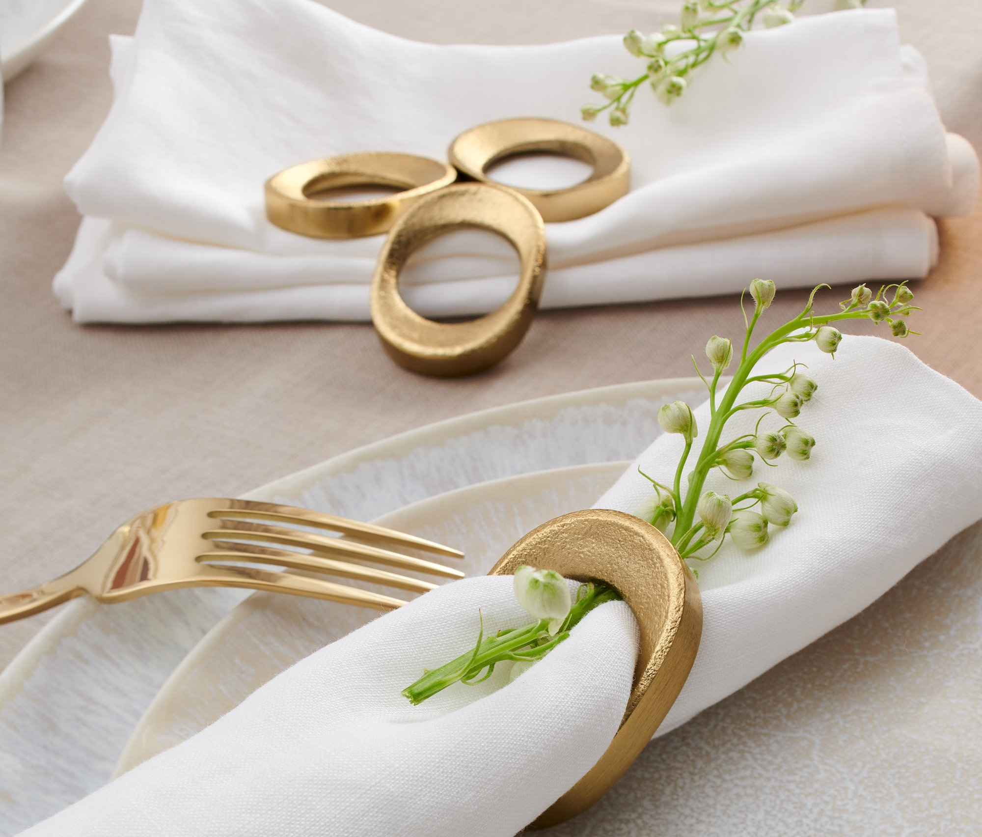 Na stole leżą białe serwetki z obrączkami na serwetki stołowe, 4 sztuki.