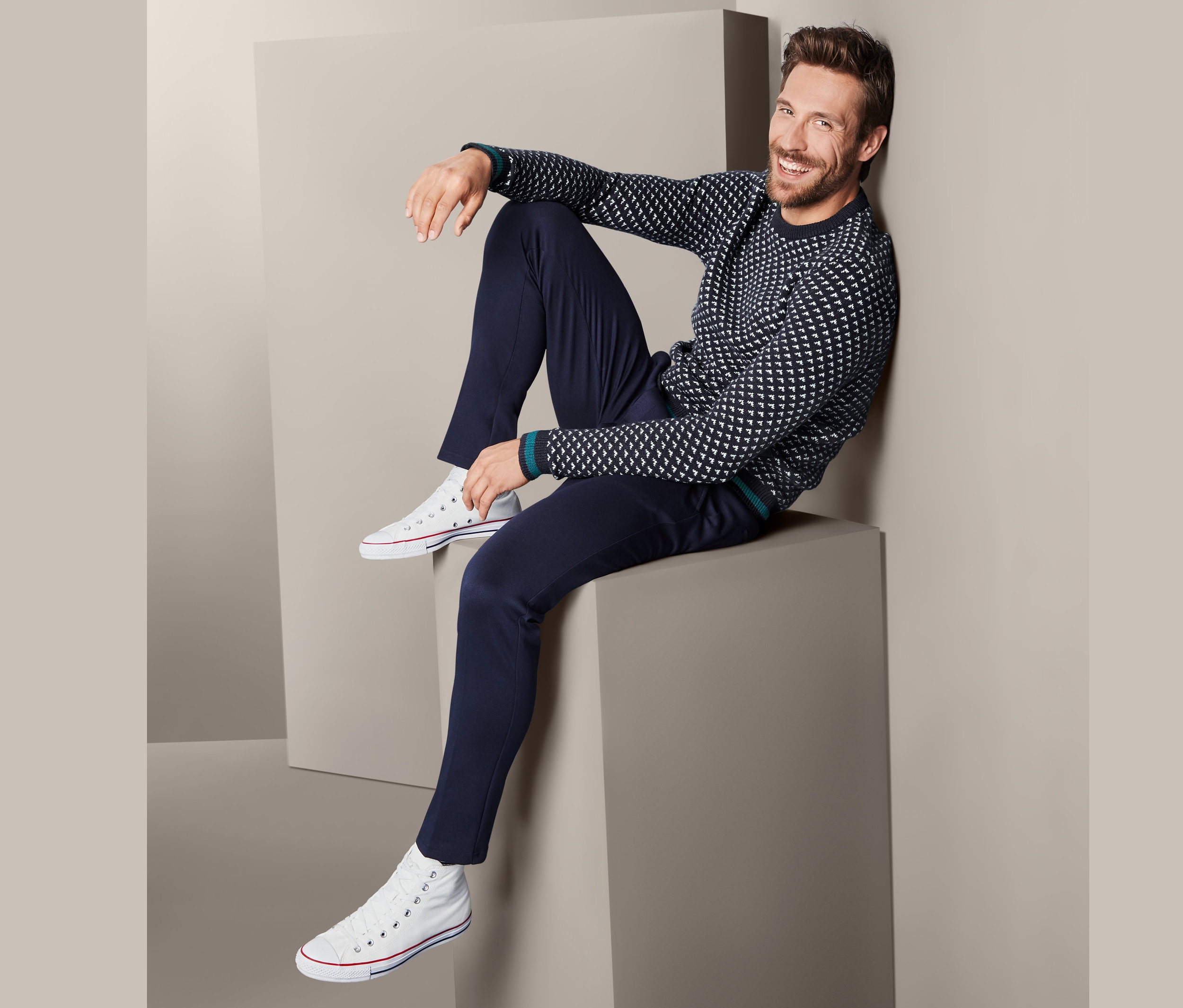 Mężczyzna siedzi na bloku w swetrze męskim z dzianiny.