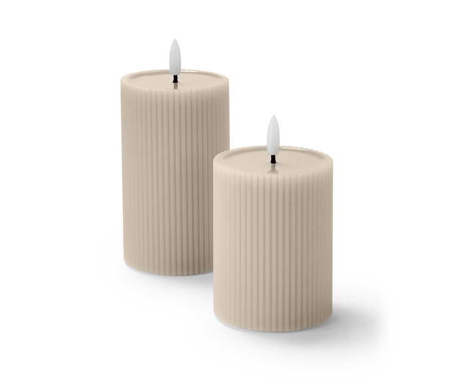 Dwie beżowe świece LED z taflą z prawdziwego wosku i żłobioną powierzchnią stoją obok siebie.
