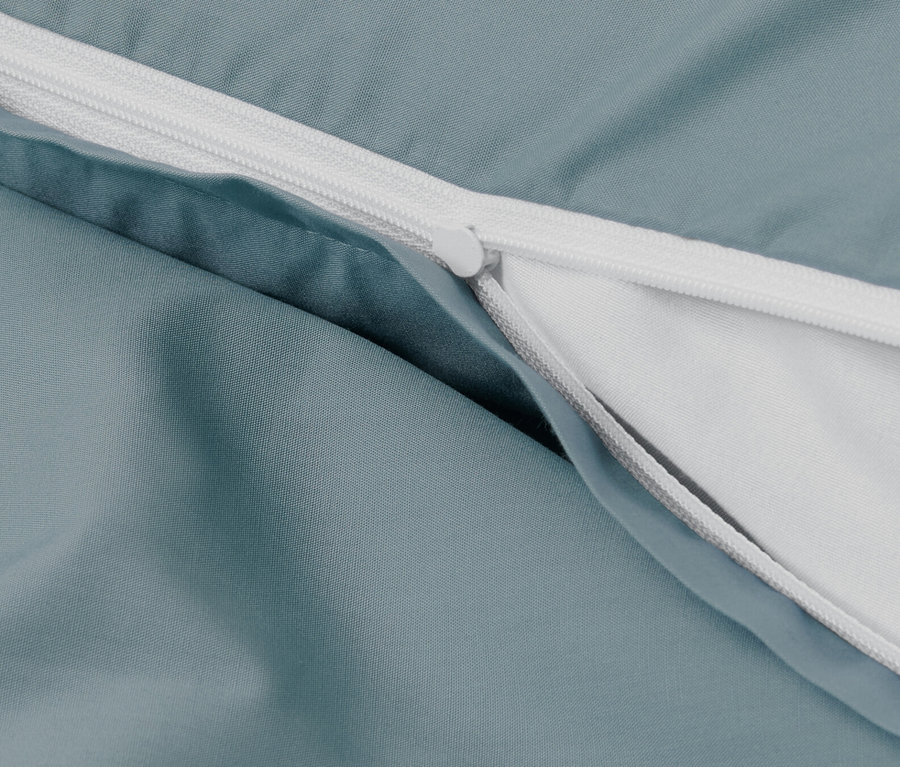 Zbliżenie na niebieską pościel perkalową z zamkiem błyskawicznym.