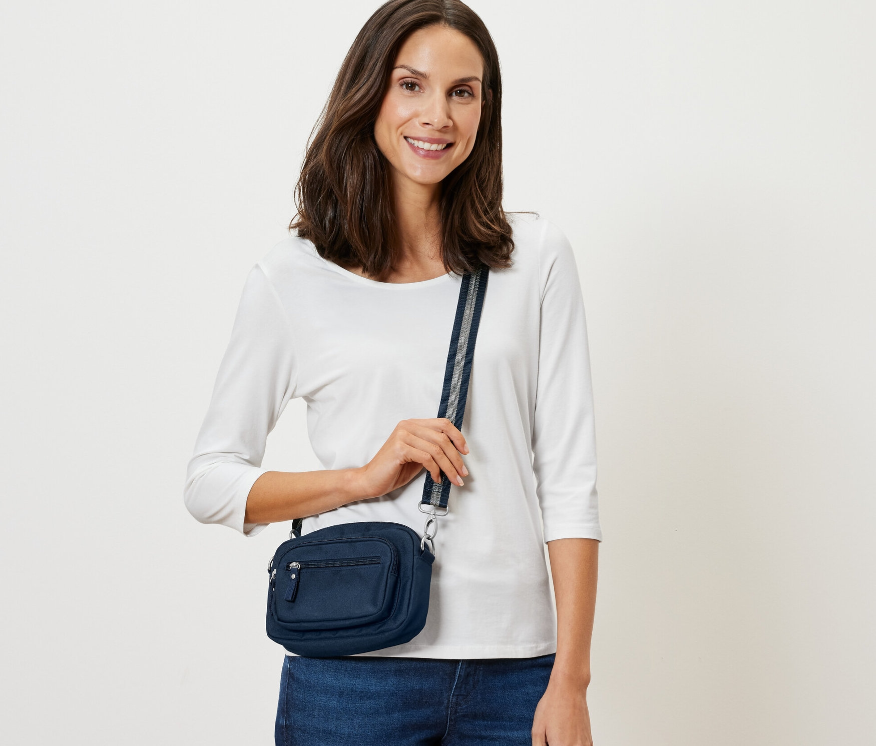 Kobieta pozuje z granatową antykradzieżową torbą na ramię lub biodra.