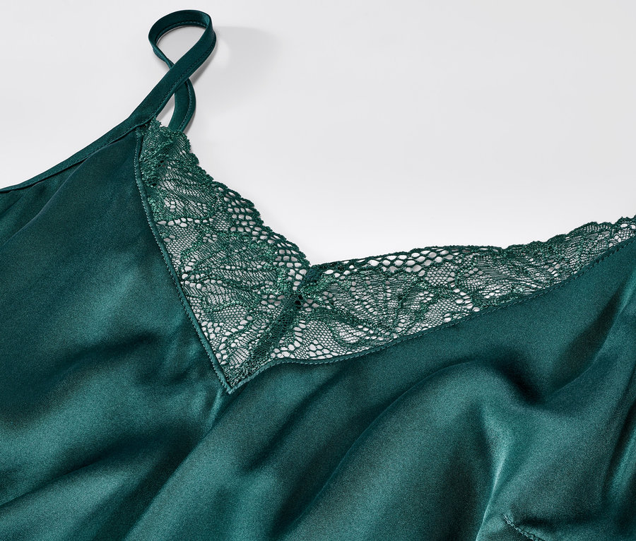 Zbliżenie na zieloną, jedwabną koszulę nocną z koronką.