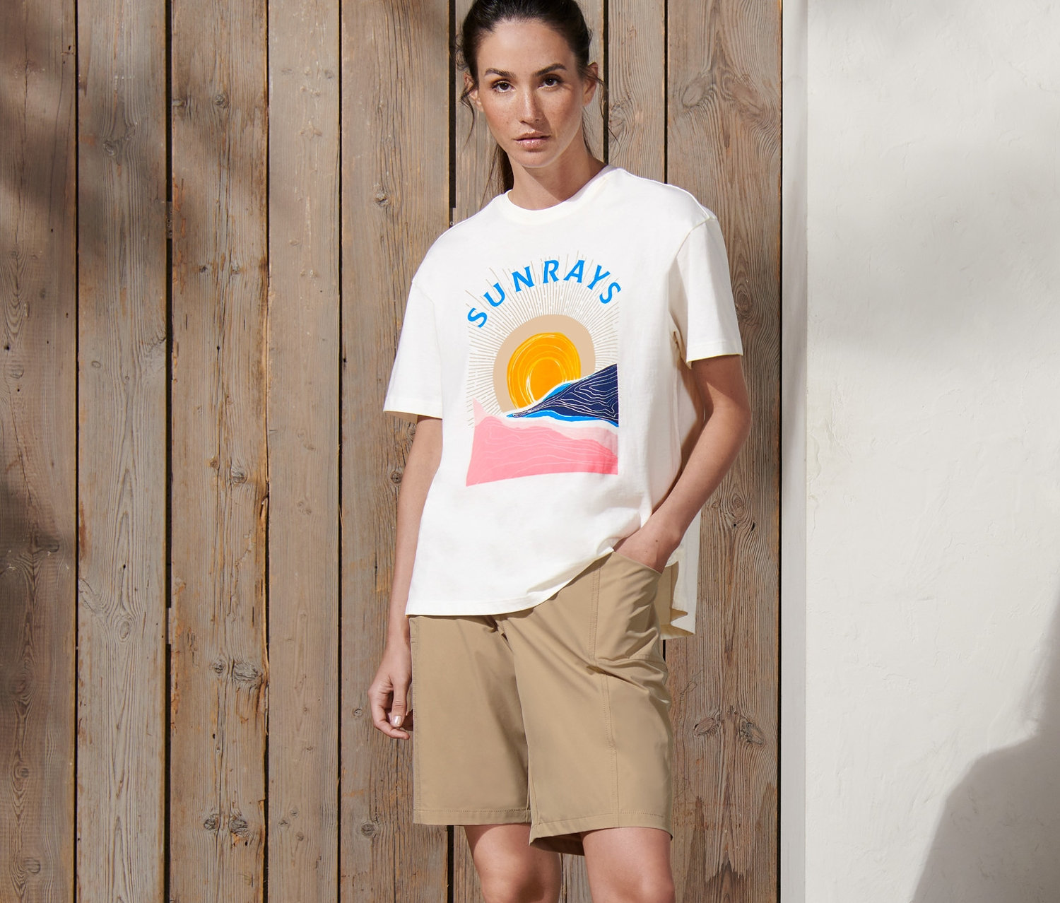 Kobieta stoi z ręką w kieszeni beżowych szortów funkcyjnych z softshellu.