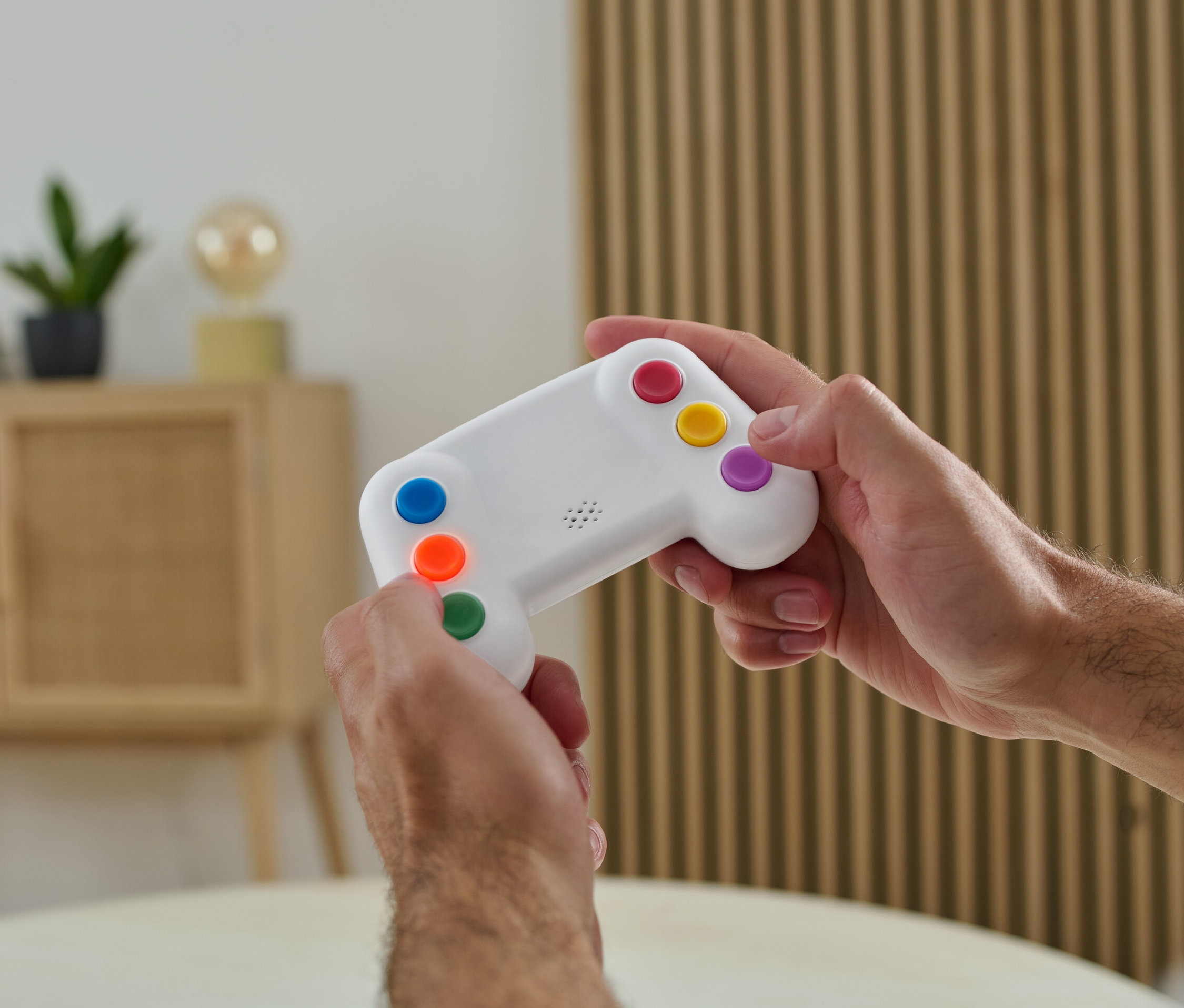 Mężczyzna trzyma w rękach elektroniczną grę do treningu pamięci z kolorowymi przyciskami.