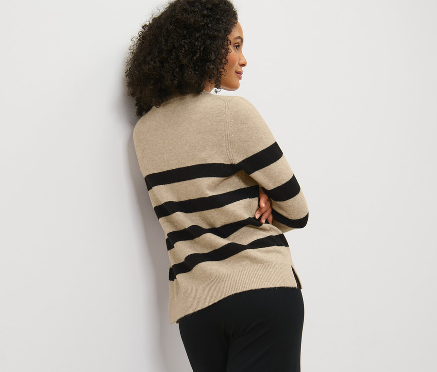 Kobieta pozuje w pasiastym swetrze.