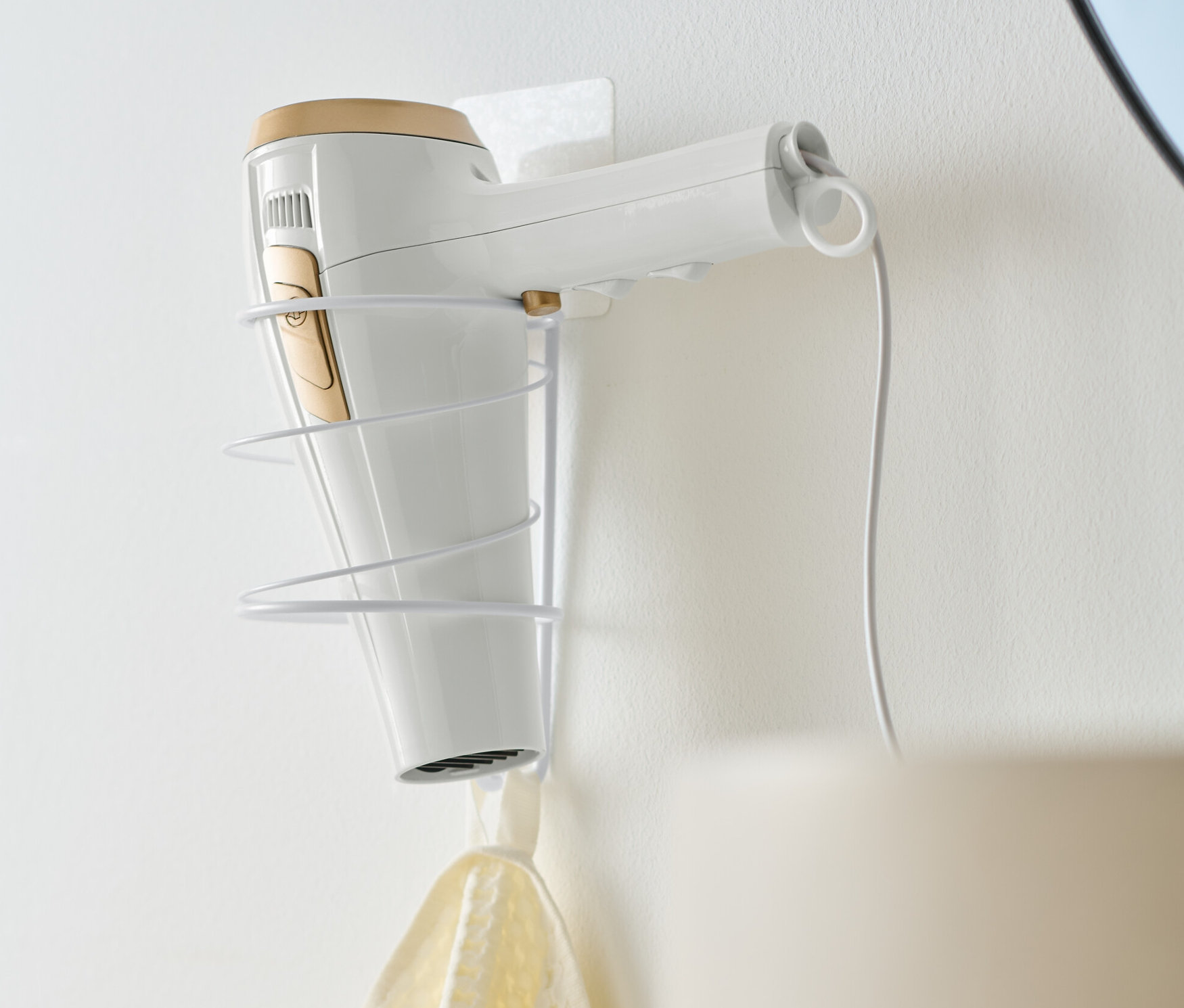 Biała suszarka do włosów umieszczona jest w uchwycie na suszarkę.