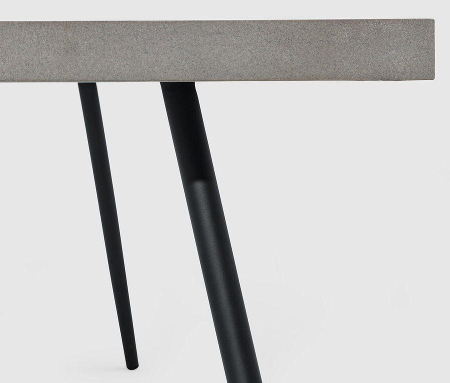 Zbliżenie na stolik kawowy z blatem z policementu i czarnymi nogami.