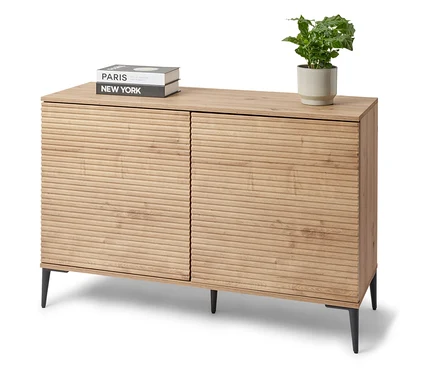 Szafka typu sideboard „REET” stoi w pokoju. Na szafce leżą książki i roślina doniczkowa.