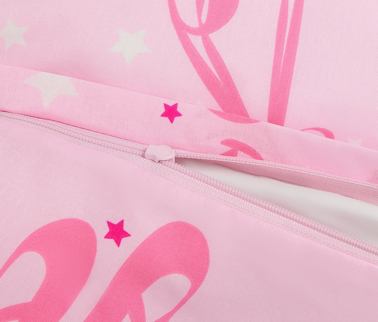 Zbliżenie na różową poszwę na kołdrę z zamkiem błyskawicznym i nadrukiem gwiazd i baletnic.