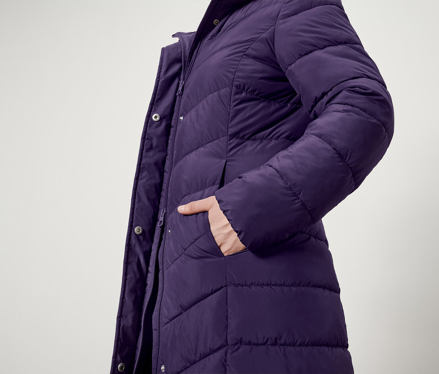 Zbliżenie na fioletową kurtkę puchową z ręką w kieszeni.