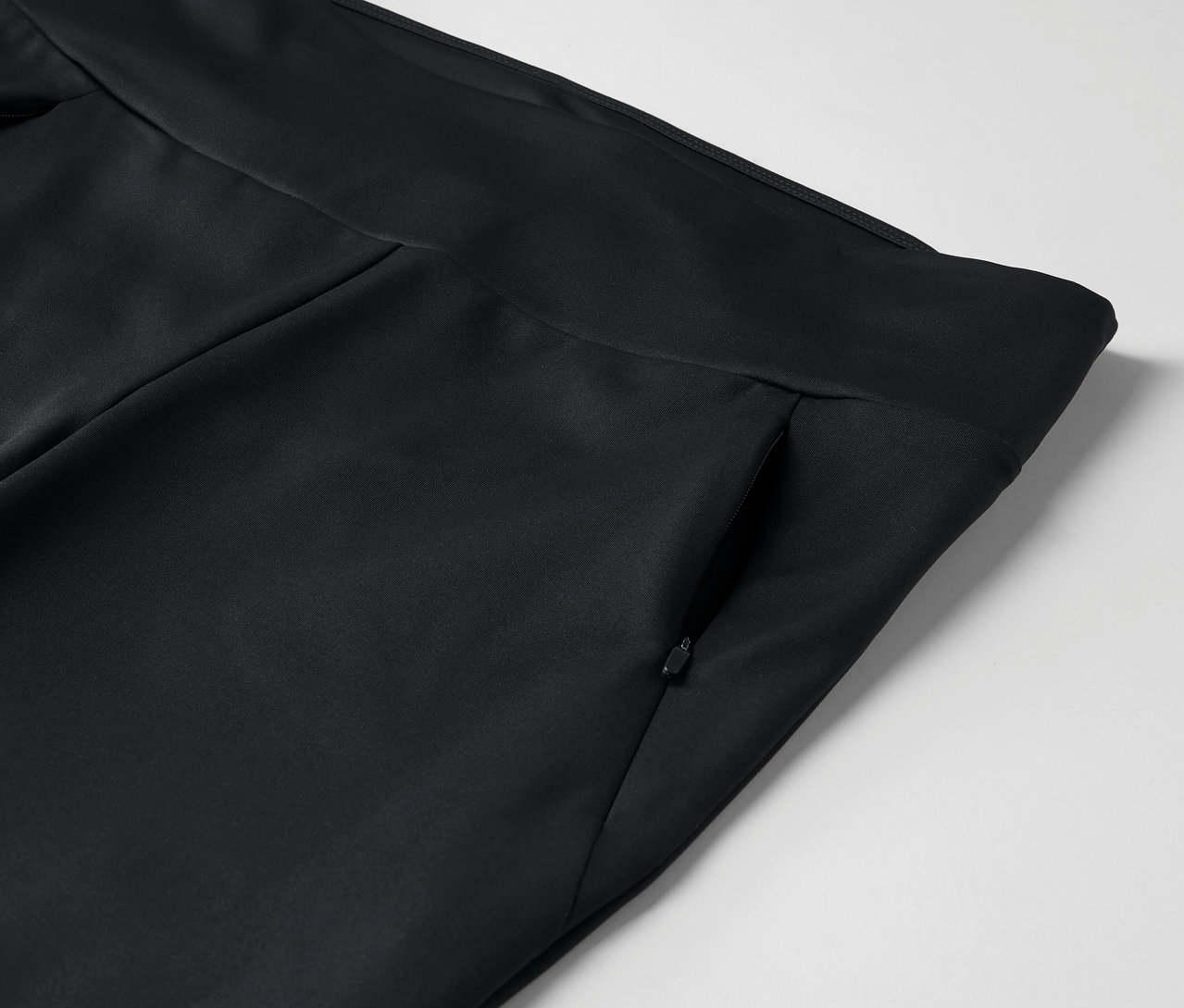 Szczegół czarnych spodni z kieszenią na zamek błyskawiczny.