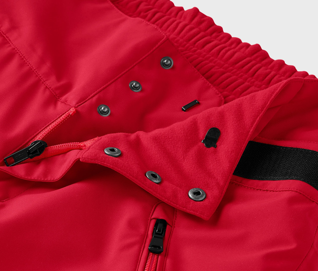 Szczegół czerwonych spodni z zamkiem błyskawicznym i zatrzaskami.