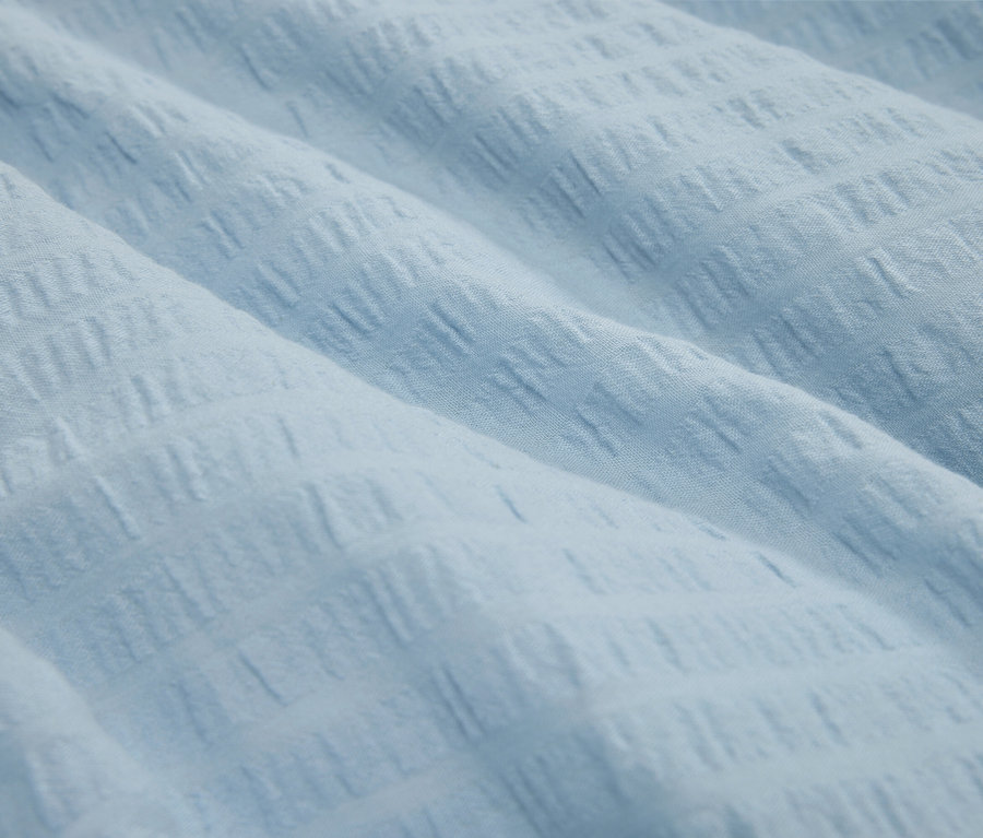 Szczegół jasnoniebieskiej teksturowanej tkaniny.
