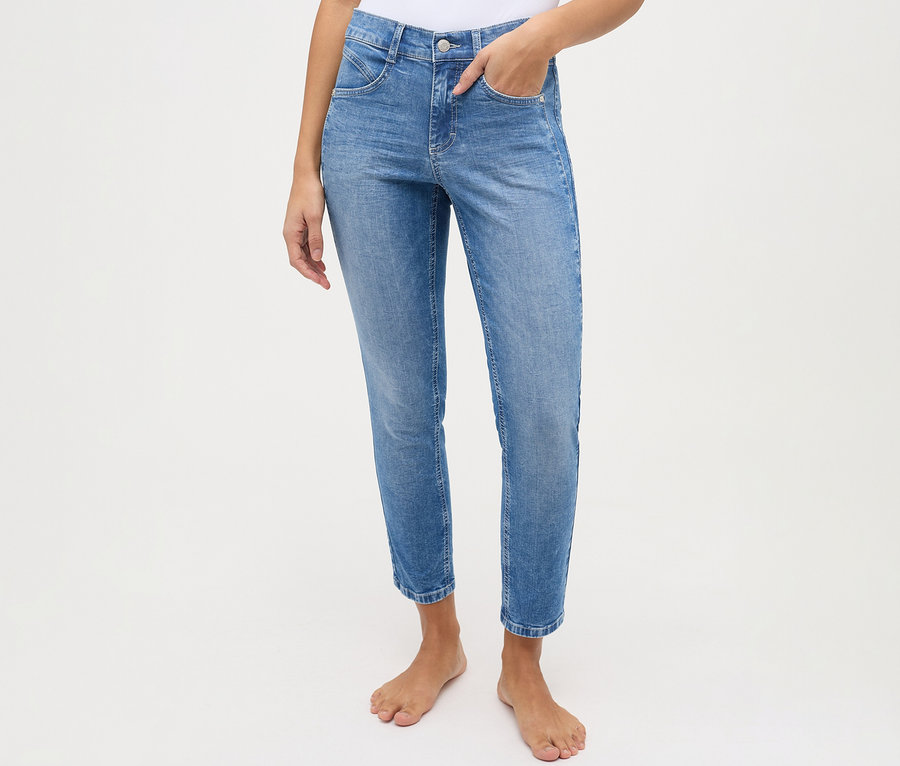 Osoba w jasnoniebieskich dżinsach Angels „Ornella Seam” Slim Fit 7/8, z jedną ręką w kieszeni, stojąca boso.