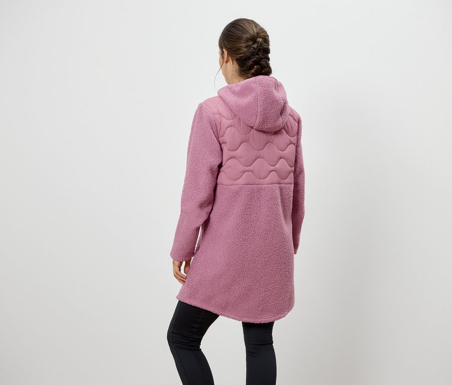 Kobieta tyłem do kamery ma na sobie różowy płaszcz z kapturem i czarne legginsy.