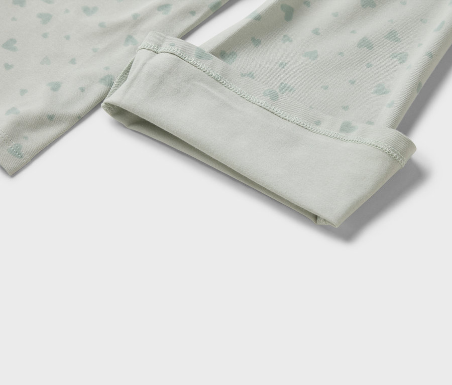 Detal jasnych, zielonych legginsów z jasnoniebieskim wzorem serc i podwiniętym brzegiem.