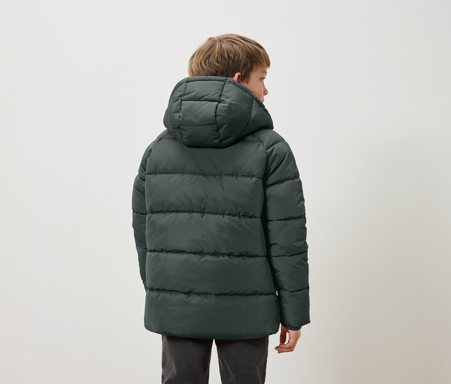 Chłopiec tyłem w ciemnozielonej kurtce puchowej z kapturem.