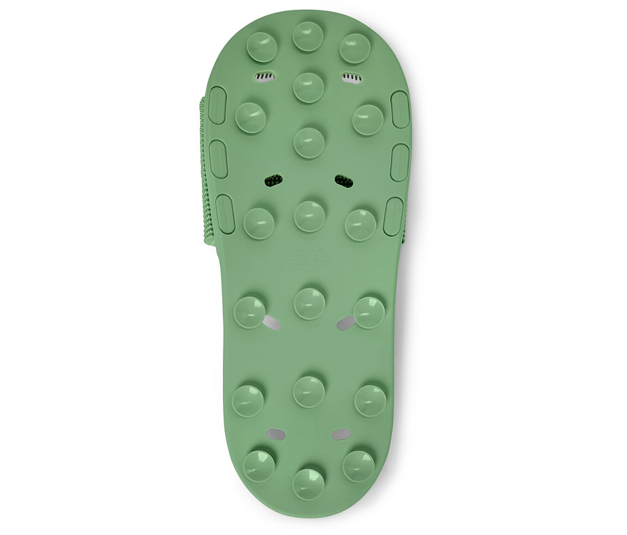 Zbliżenie pojedynczego zielonego buta do kąpieli z wypustkami na białym tle.