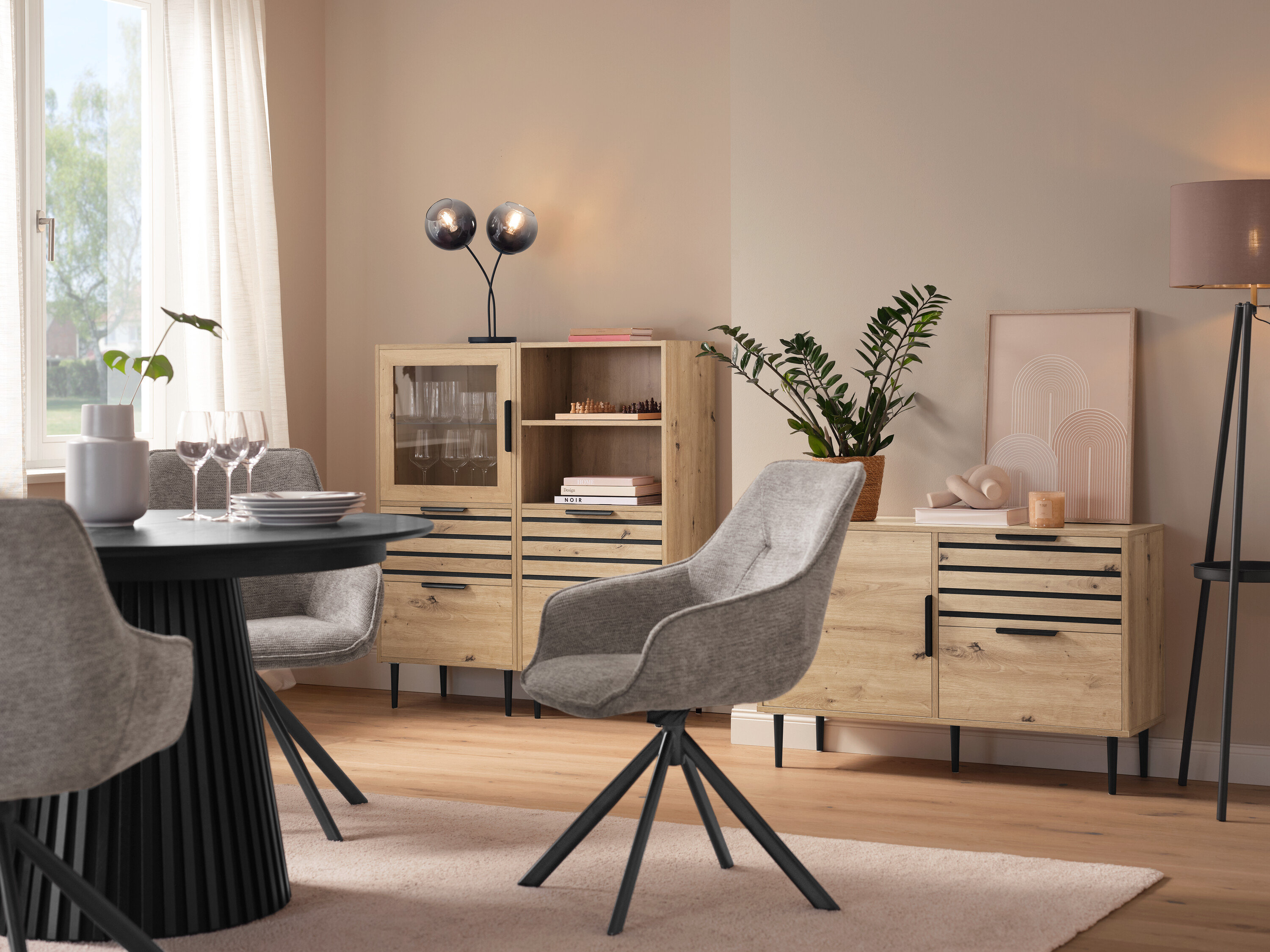 Jadalnia z okrągłym stołem, szarymi krzesłami, witryną »BAAKEN« z przeszklonymi drzwiami, regałem »BAAKEN« z szufladami i sideboardem z szufladami.