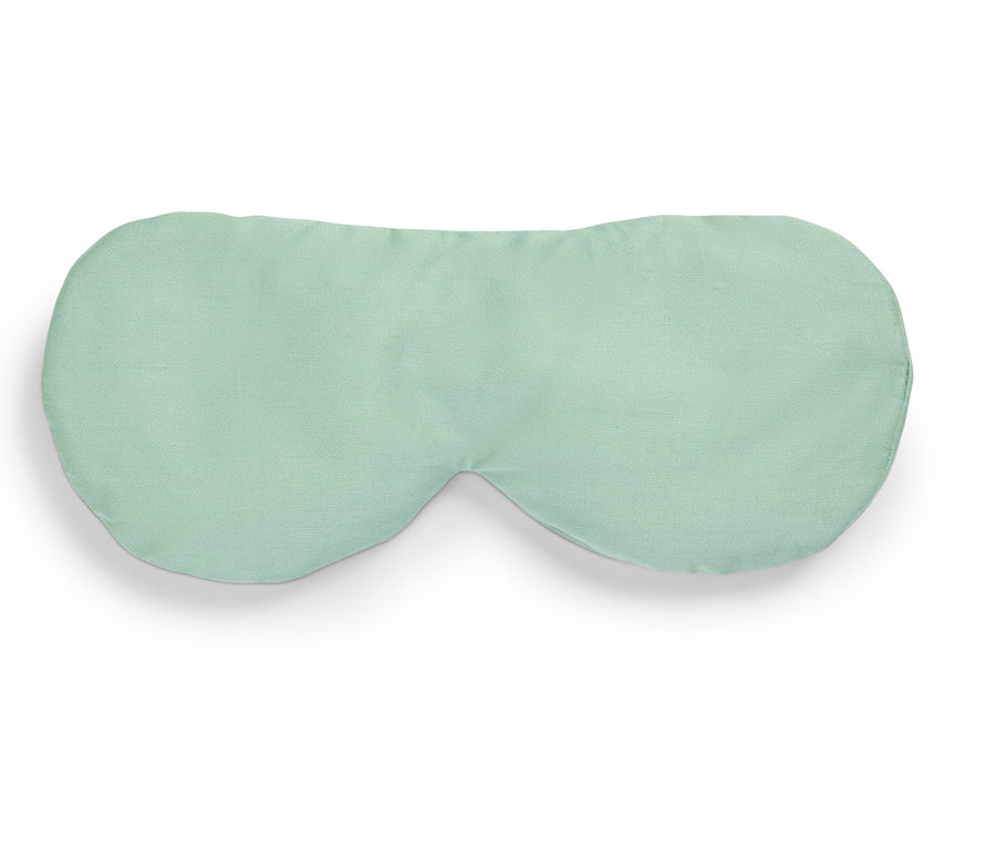 Jasnozielona maska do spania leży na białym tle.
