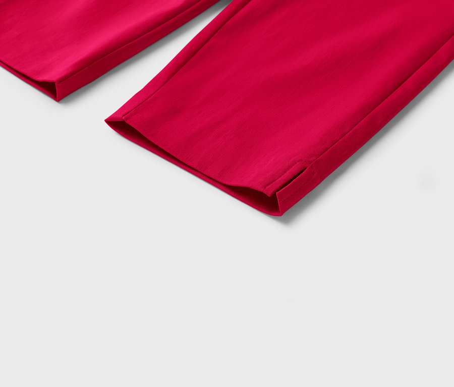 Zbliżenie na nogawki czerwonych spodni z małymi rozcięciami u dołu na białym tle.